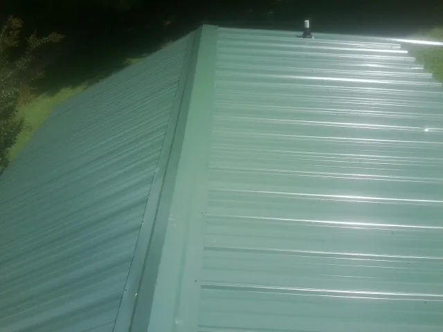 New green metal panels meeting at the ridge of a roof — Flat Roof Repair work by our crew in New Hope