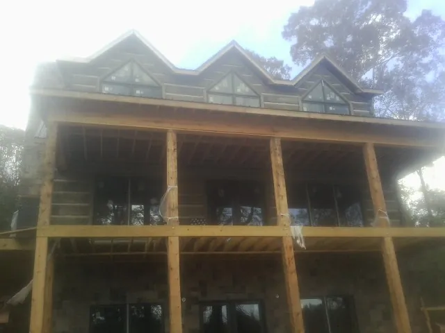 Dormers and porch framing on a large log home under construction — Roof Coating work by our crew in New Hope