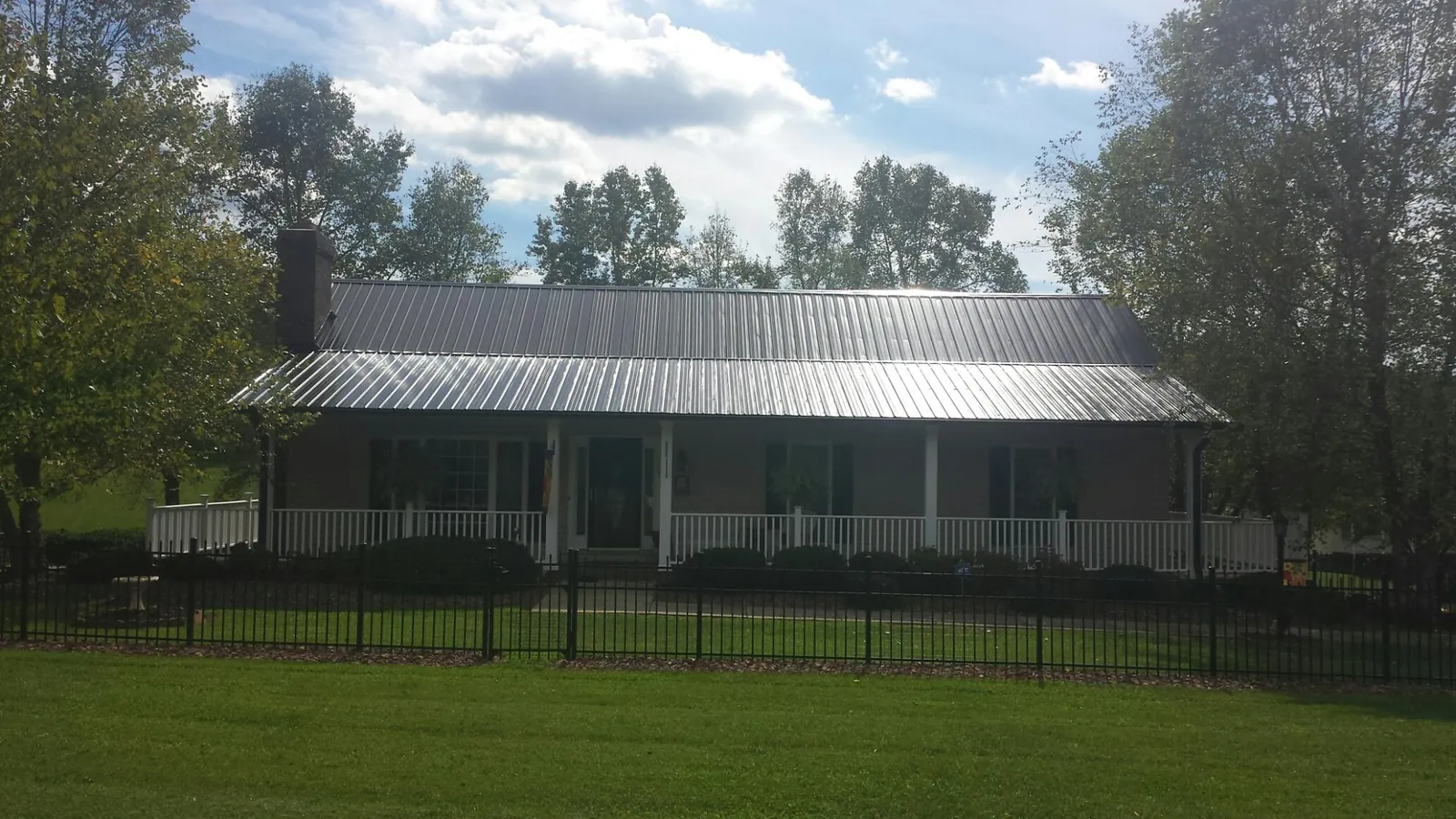 Gray metal roof on a brick ranch with a full width front porch — Gutter Guard Installation work by our crew in New Hope