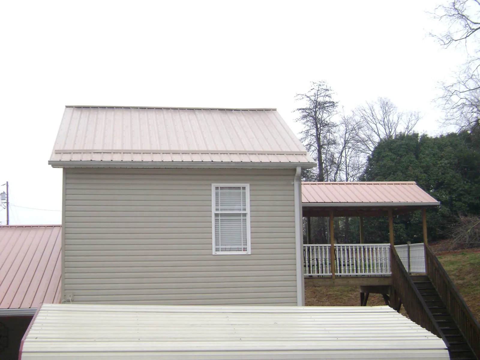 Tan metal roofs on a two story addition and attached porch, from a Roof Replacement job in New Hope