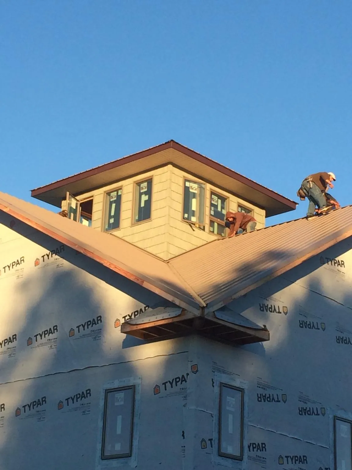 Roofers working around a rooftop cupola on a new metal roof at sunset — Roof Waterproofing in New Hope by Roofing Brothers